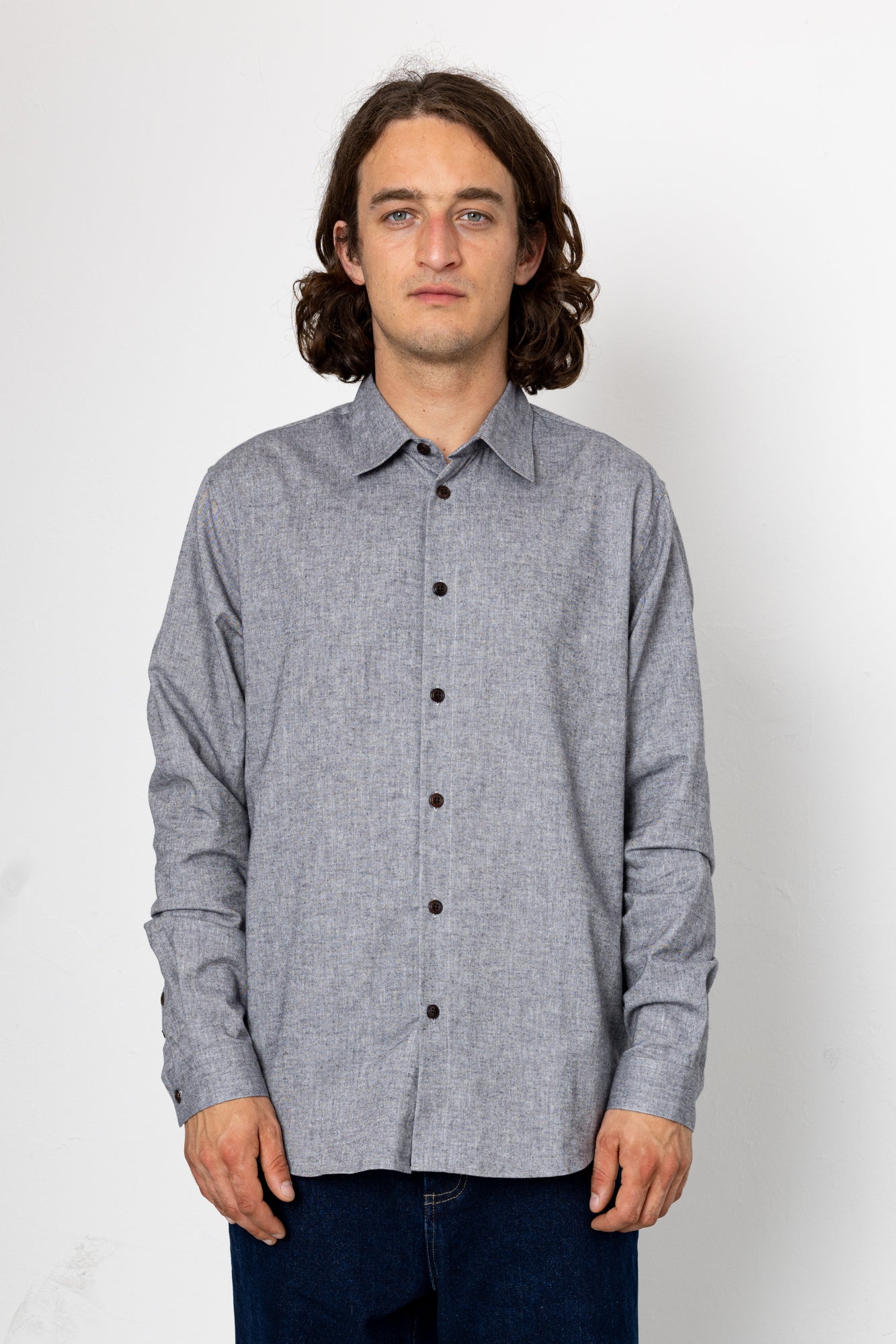 Man wearing a gray button-up shirt against a white background