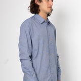 Man wearing a blue patterned shirt against a white background