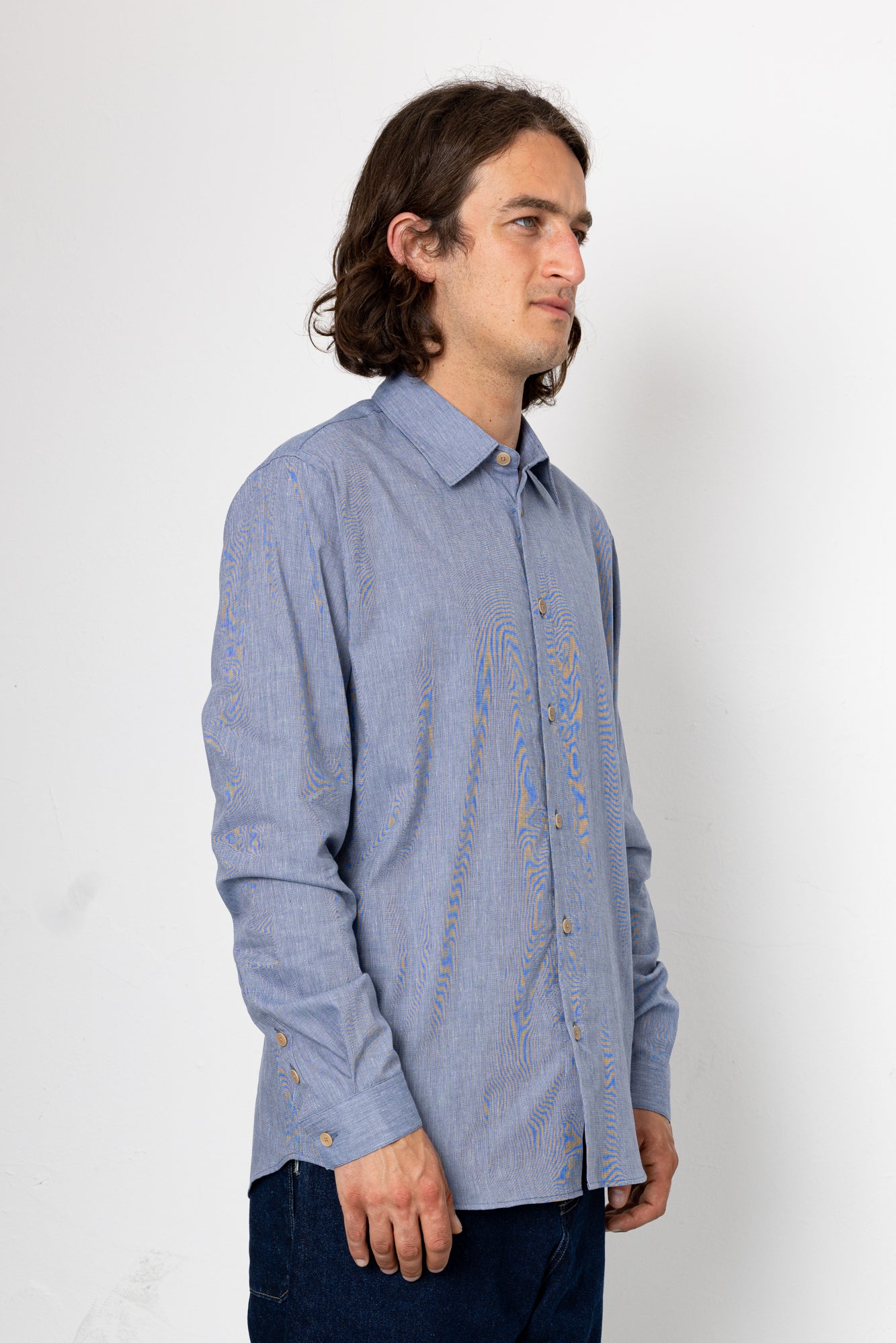 Man wearing a blue patterned shirt against a white background