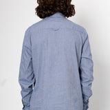 Person wearing a blue denim shirt with a plain white background