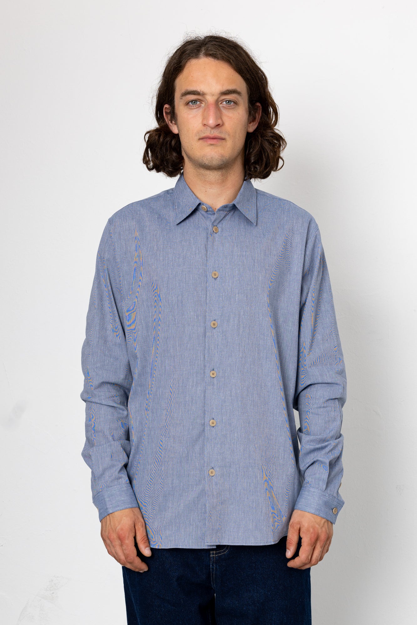 Man wearing a blue patterned shirt against a white background