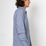 Man wearing a light blue button-up shirt against a white background