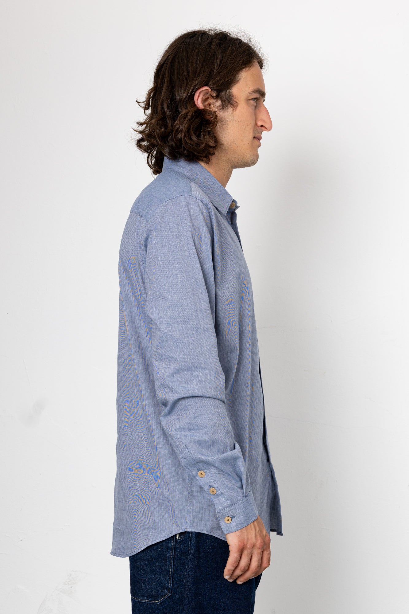 Man wearing a light blue button-up shirt against a white background