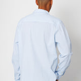 Person wearing a light blue shirt from behind on a plain background
