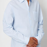 Man wearing a light blue striped shirt against a plain background