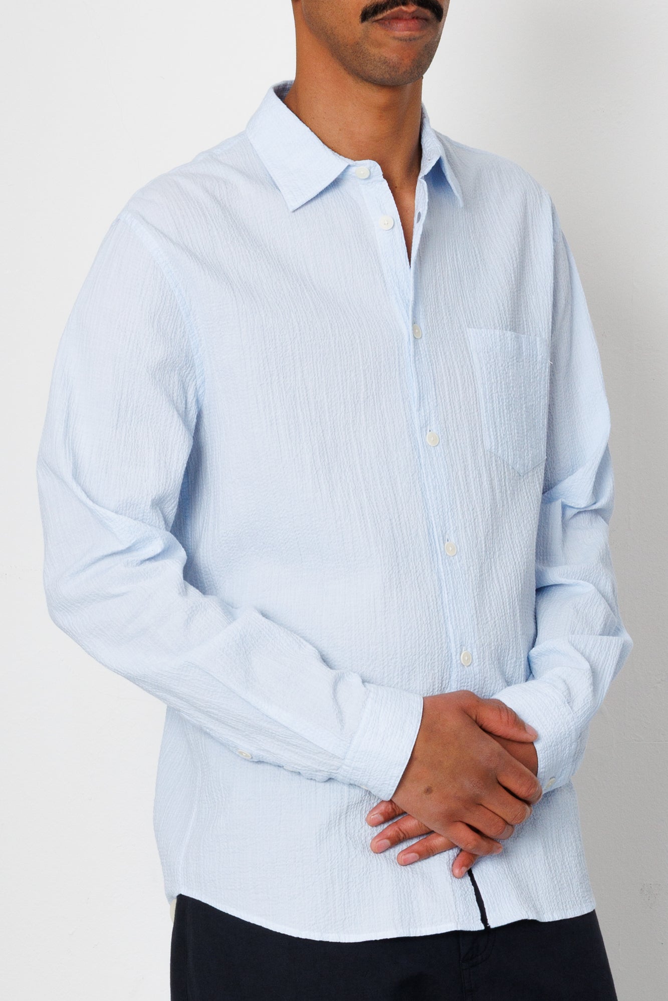 Man wearing a light blue striped shirt against a plain background