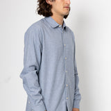 Man wearing a light blue button-up shirt against a white background