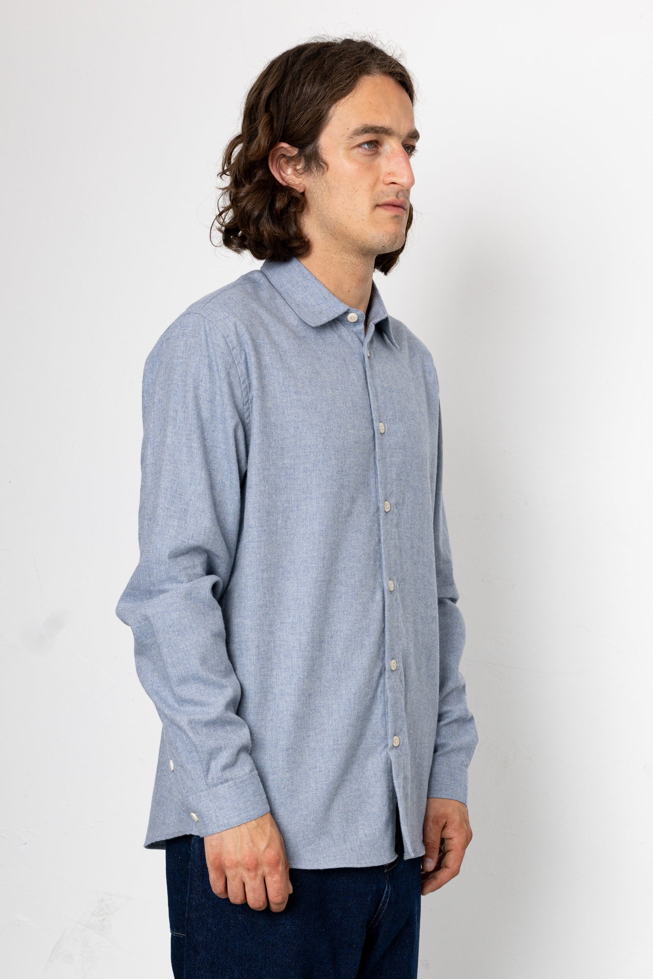 Man wearing a light blue button-up shirt against a white background
