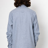 Person wearing a light blue button-up shirt from behind on a white background