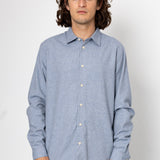 Man wearing a light blue button-up shirt against a white background