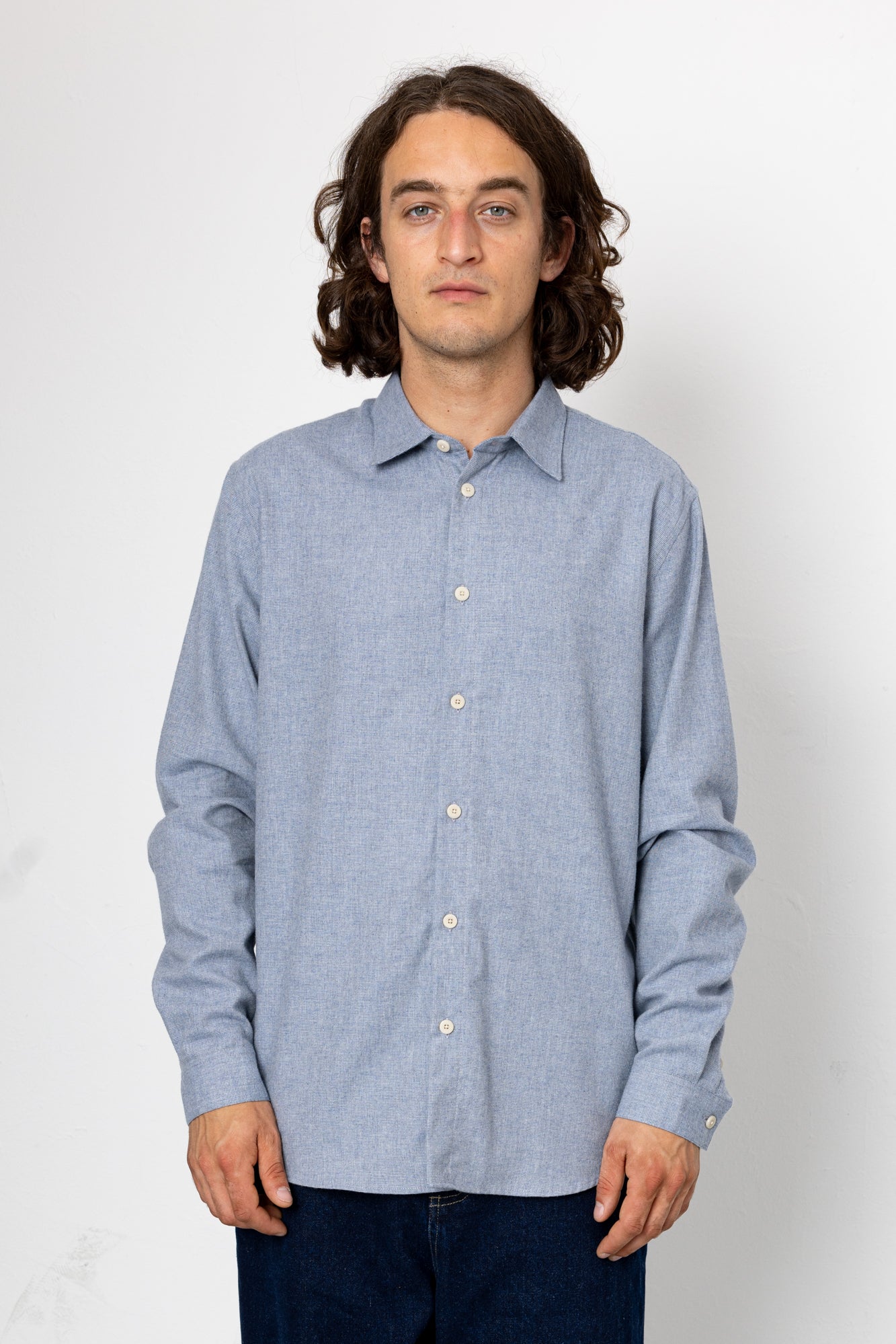 Man wearing a light blue button-up shirt against a white background