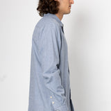 Man wearing a light blue shirt with rolled-up sleeves on a white background