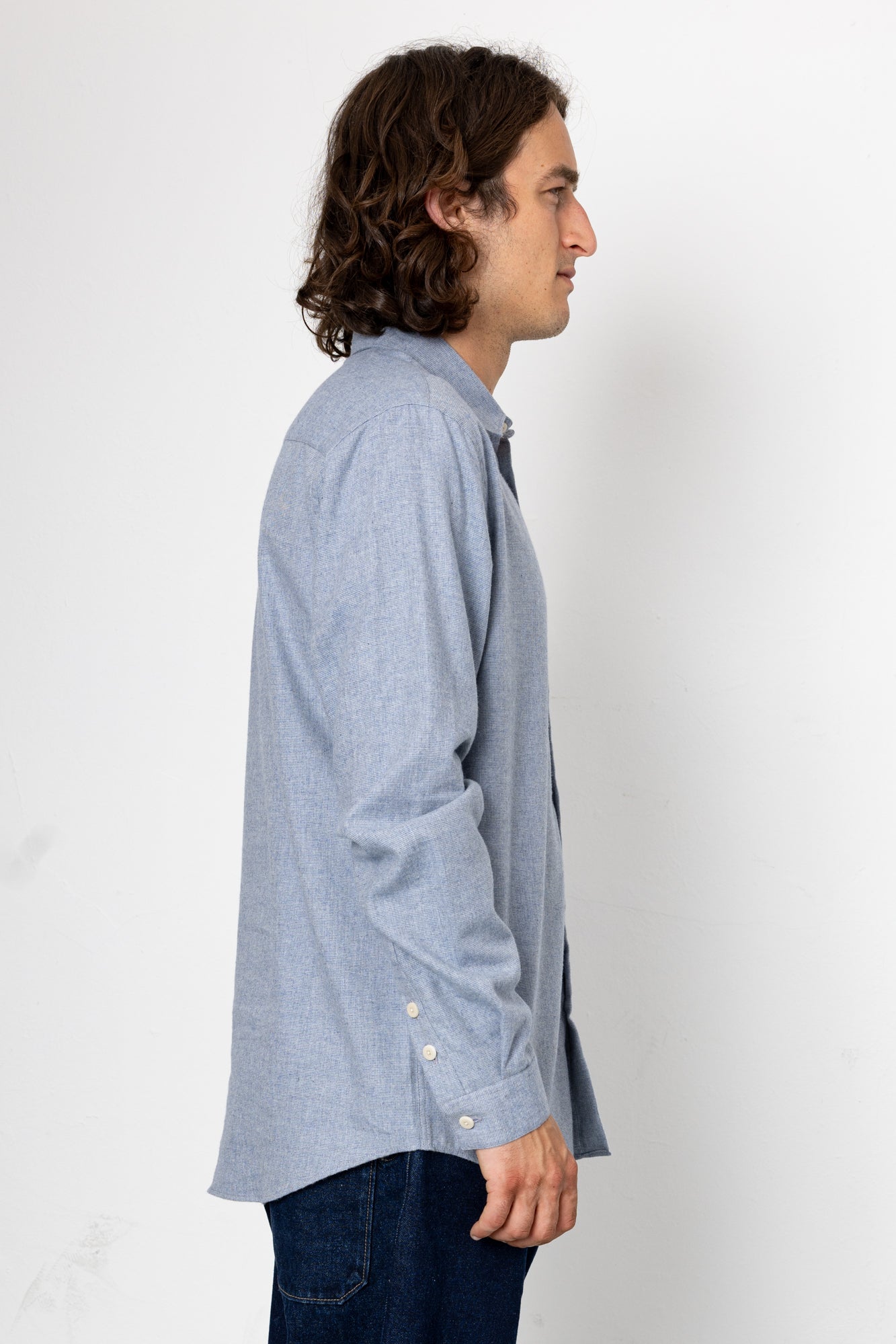 Man wearing a light blue shirt with rolled-up sleeves on a white background