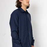 Man wearing a dark blue textured shirt against a white background