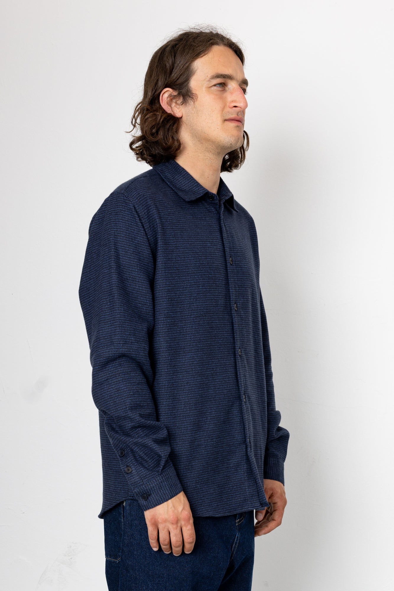 Man wearing a dark blue textured shirt against a white background