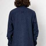 Person wearing a blue textured shirt against a white background