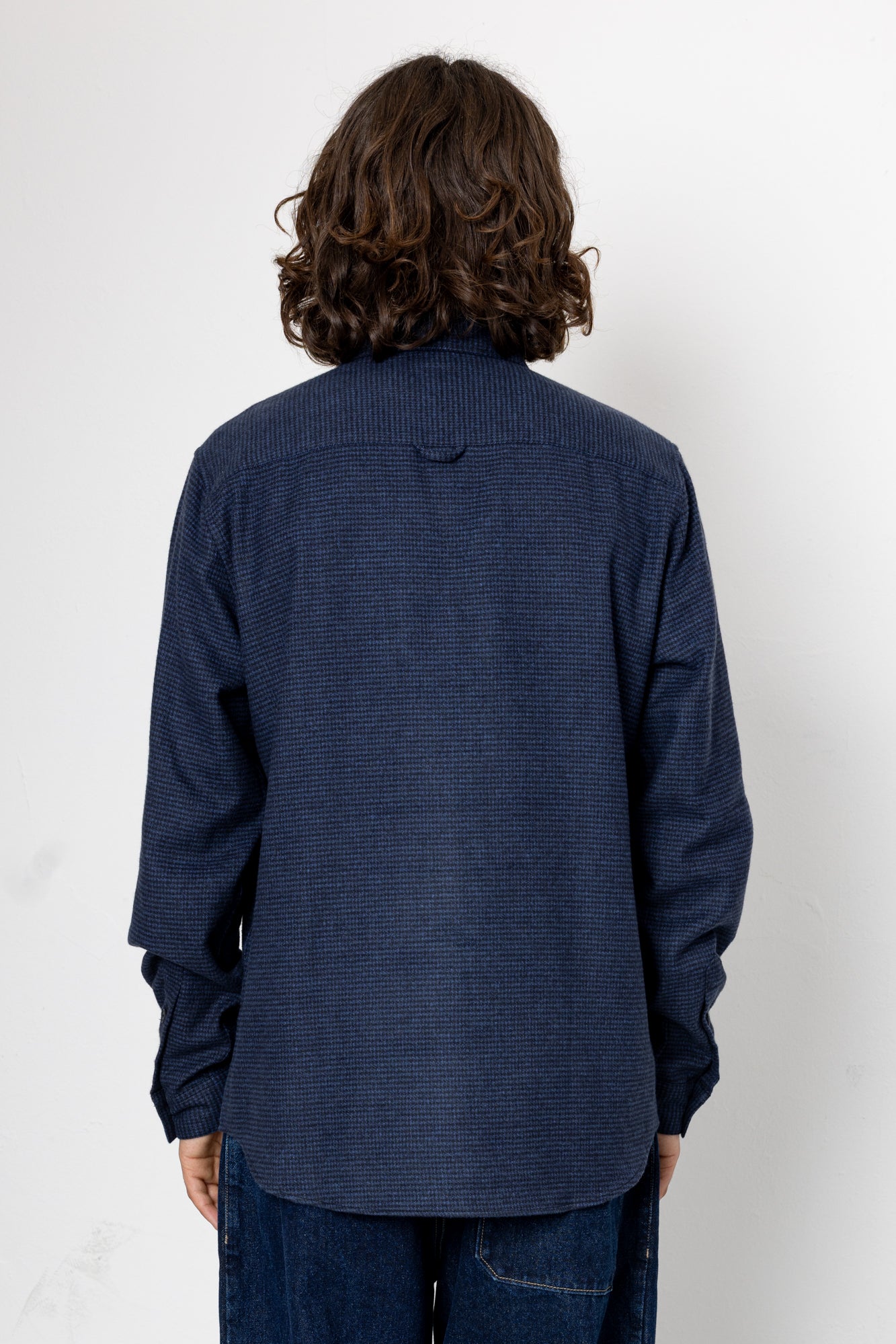 Person wearing a blue textured shirt against a white background