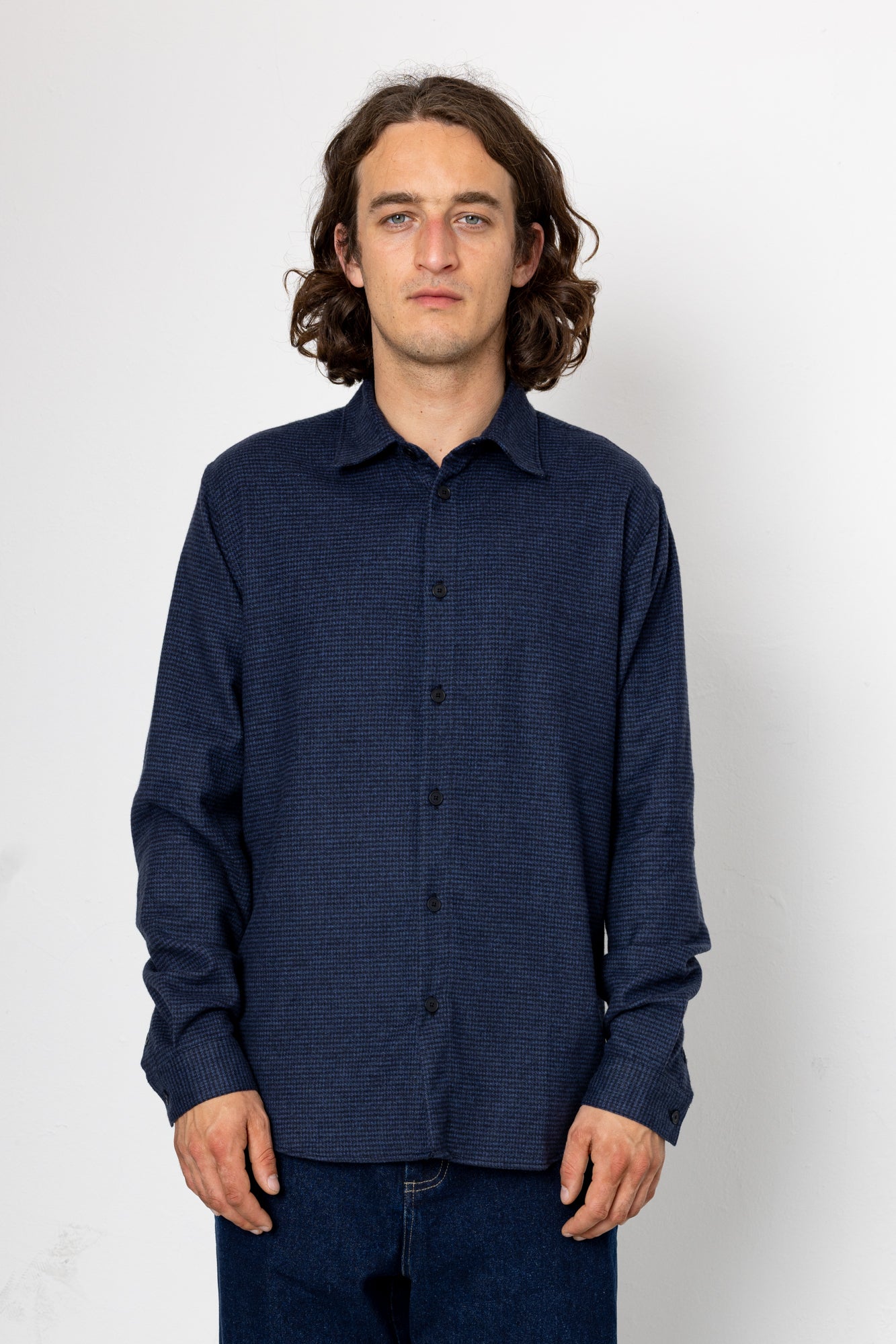 Man wearing a dark blue textured shirt against a white background