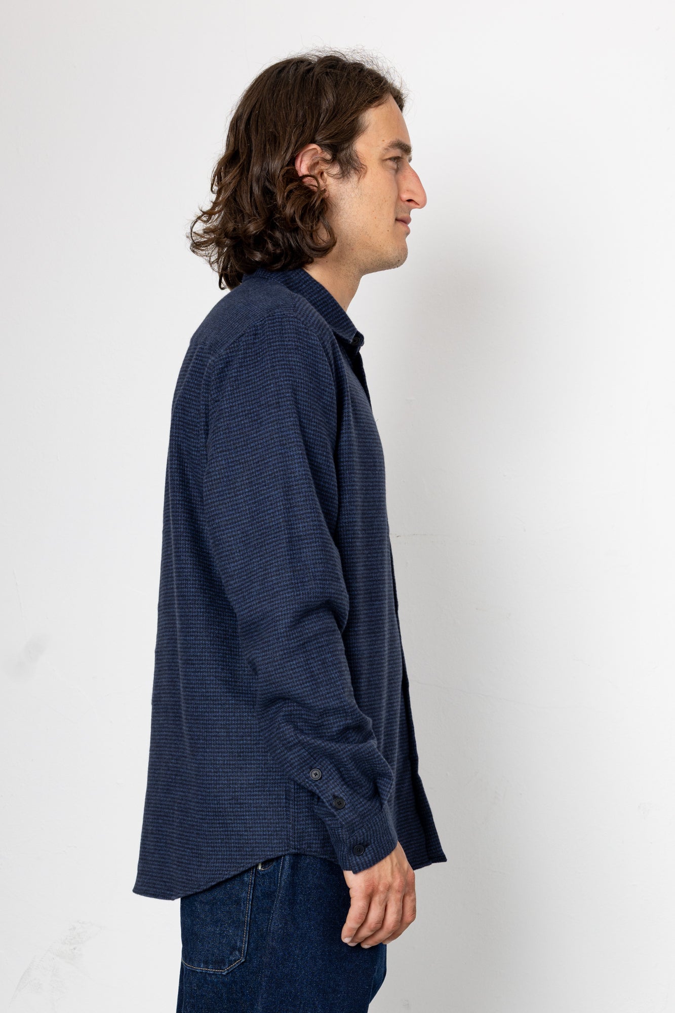 Man wearing a dark blue textured shirt against a white background