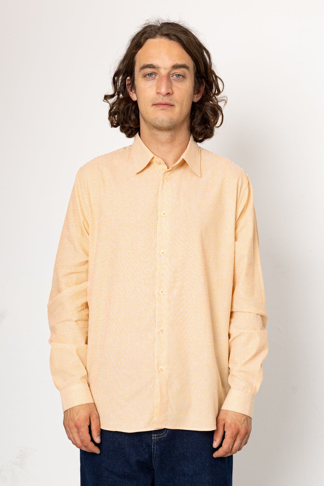 Man wearing a light pink shirt against a white background