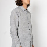 Man wearing a gray button-up shirt against a white background