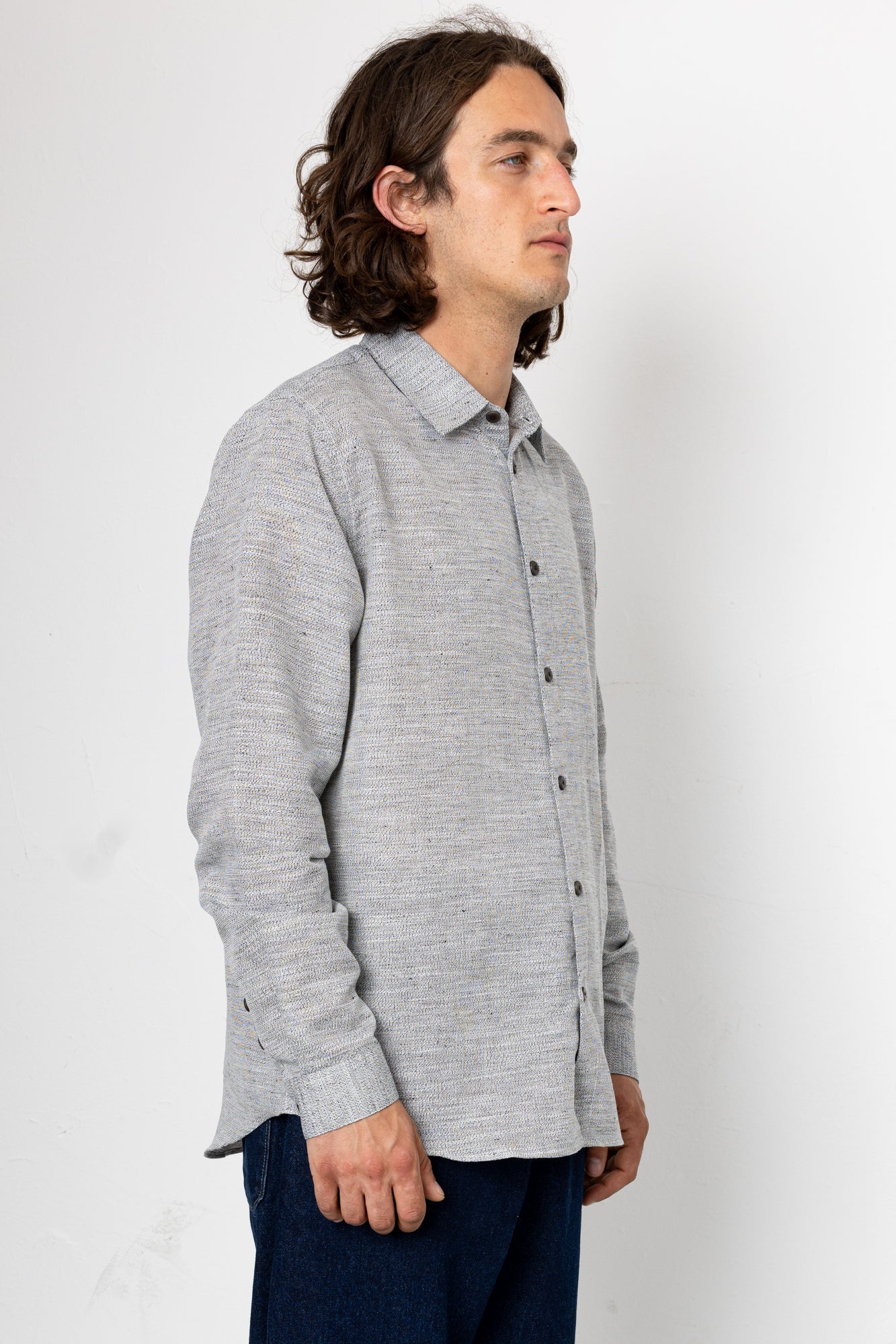 Man wearing a gray button-up shirt against a white background