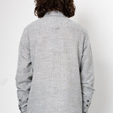Person wearing a gray textured shirt with long hair on a white background