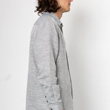 Man wearing a gray cardigan over a dark shirt on a white background