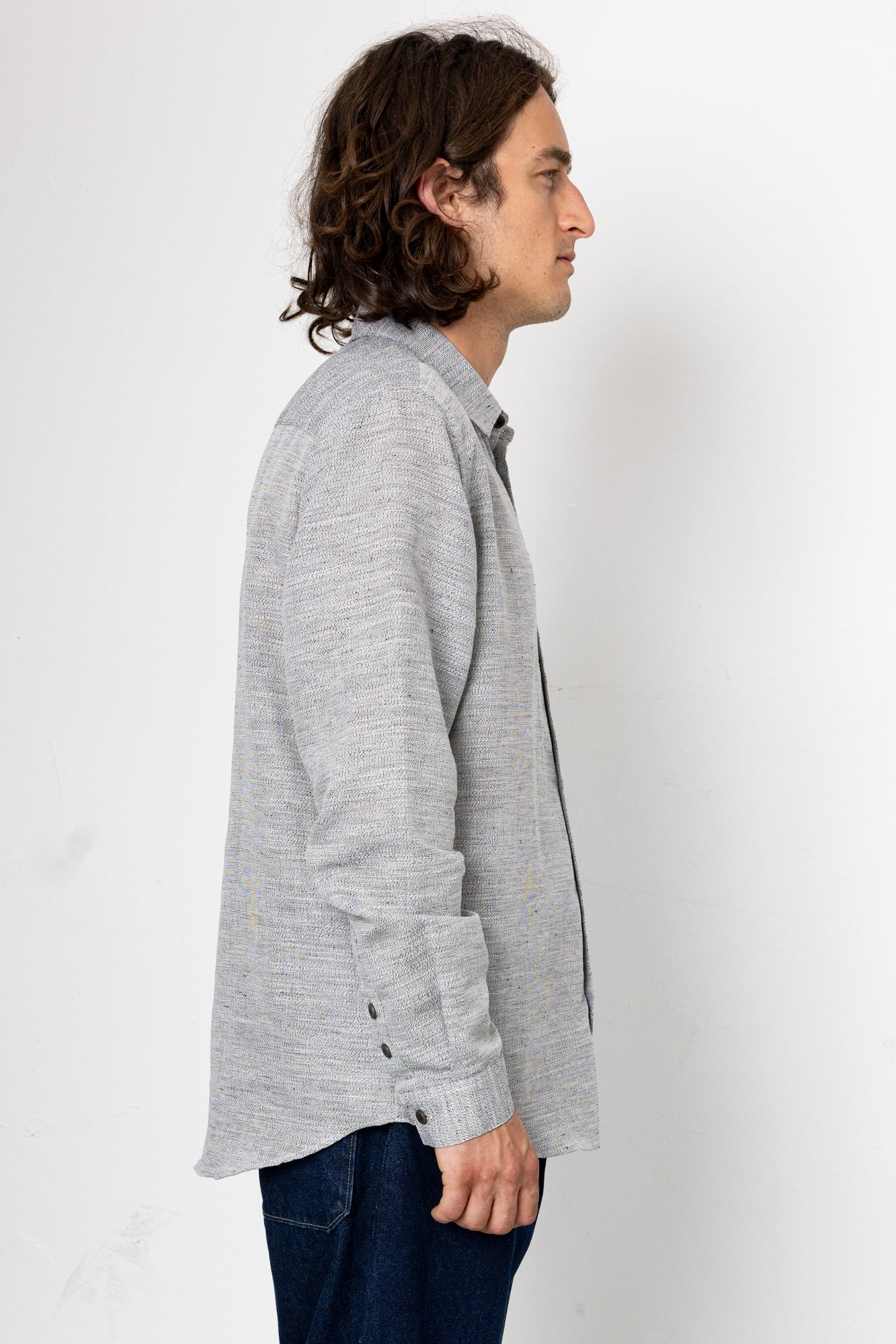 Man wearing a gray cardigan over a dark shirt on a white background