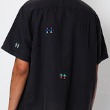 Back view of a black shirt with embroidered people detailing.