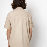 Person wearing a beige short-sleeve shirt against a white background