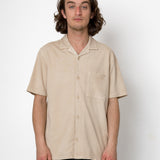 Man wearing a beige short-sleeve shirt against a white background