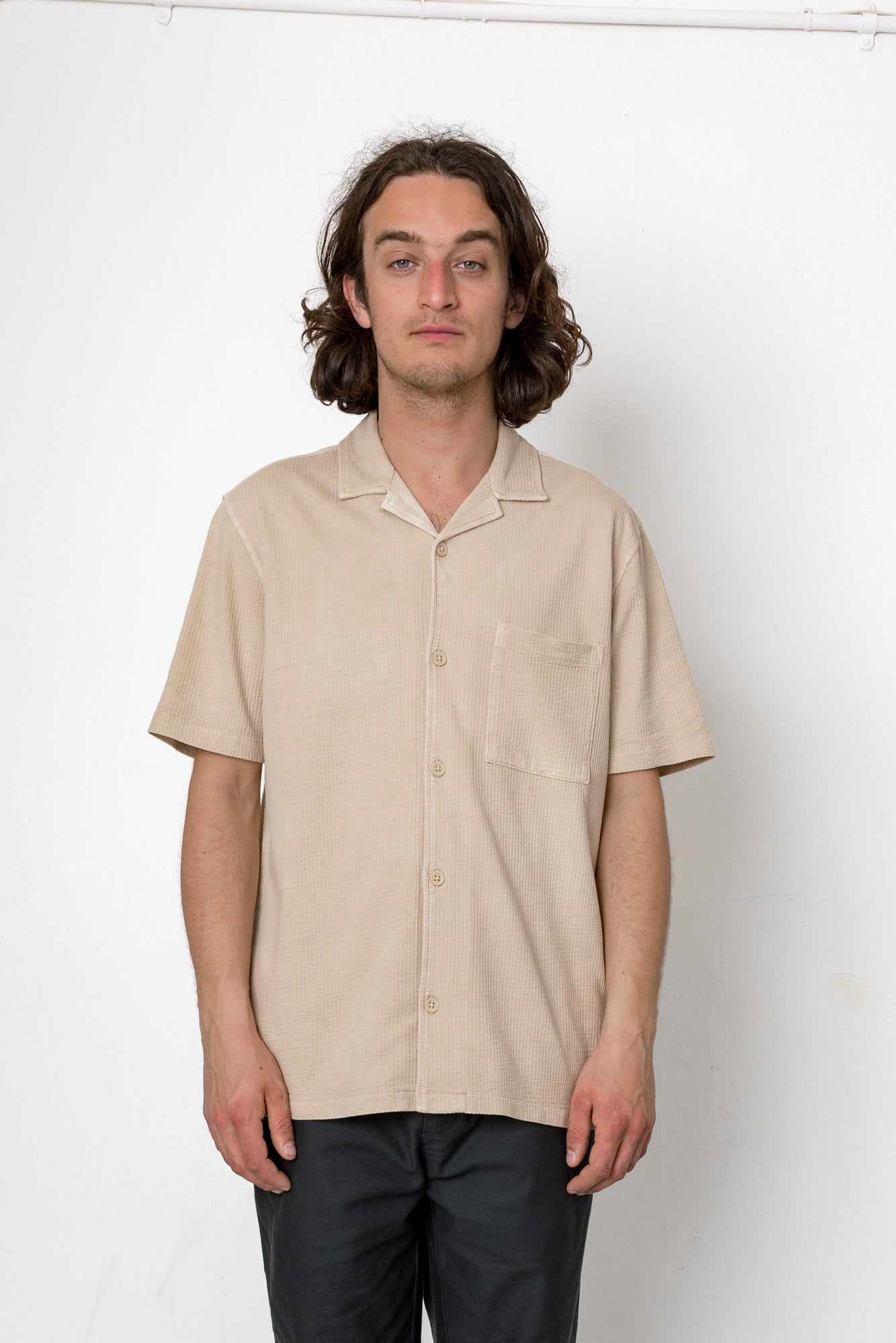 Man wearing a beige short-sleeve shirt against a white background