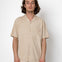 Man wearing a beige short-sleeve shirt against a white background