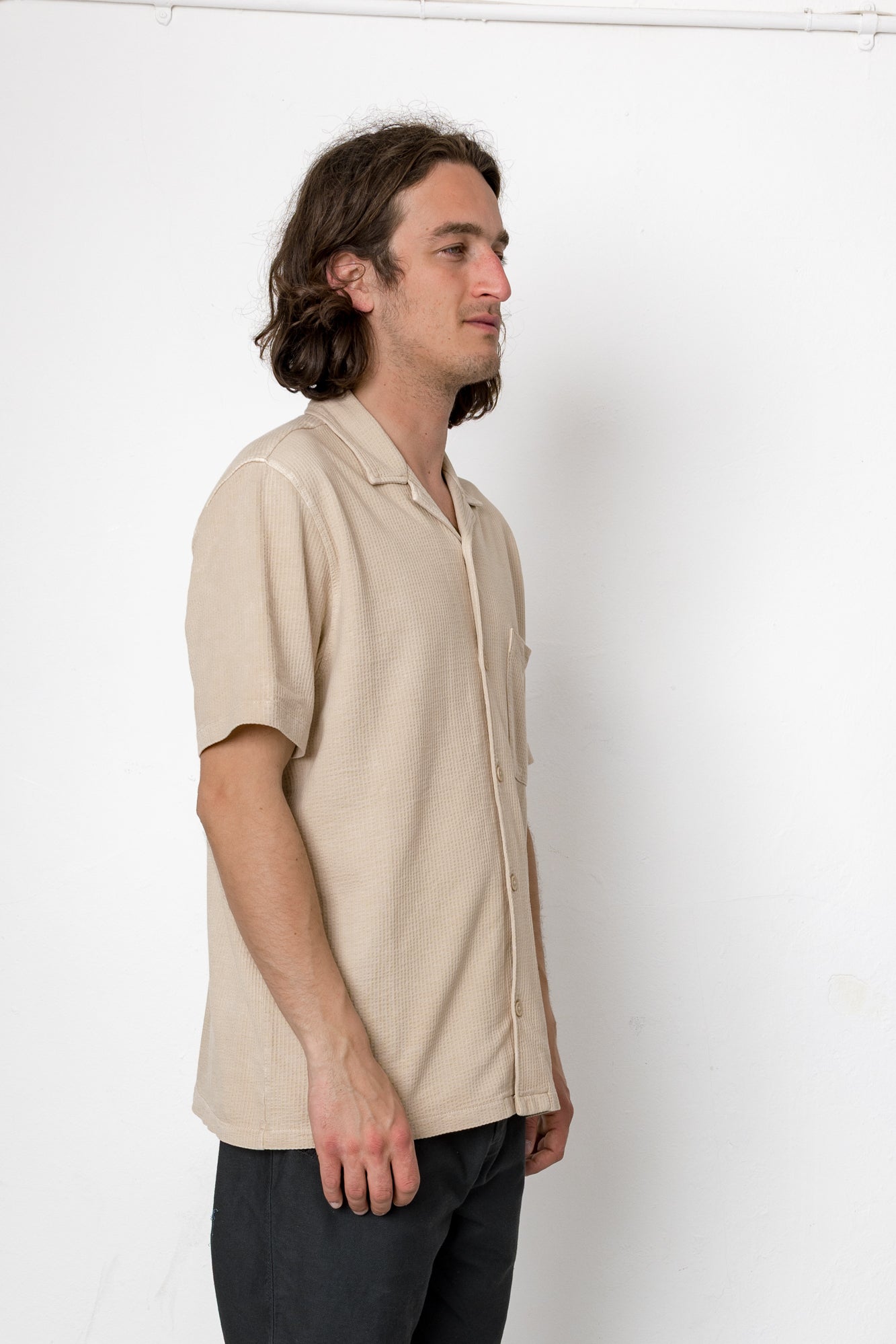Man wearing a beige short-sleeve shirt against a white background