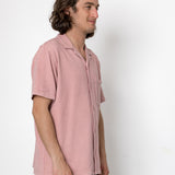 Man wearing a pink shirt against a white background