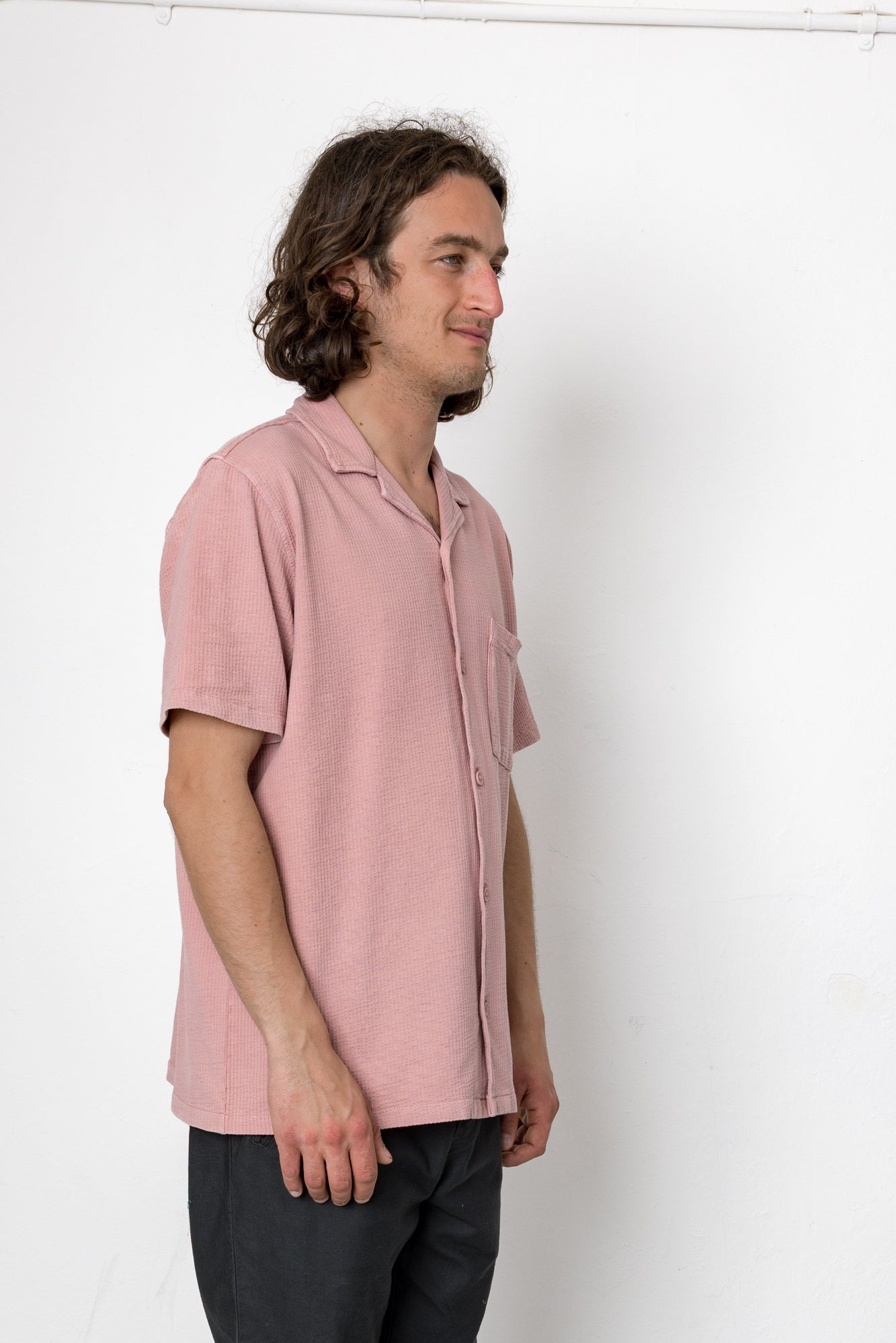 Man wearing a pink shirt against a white background