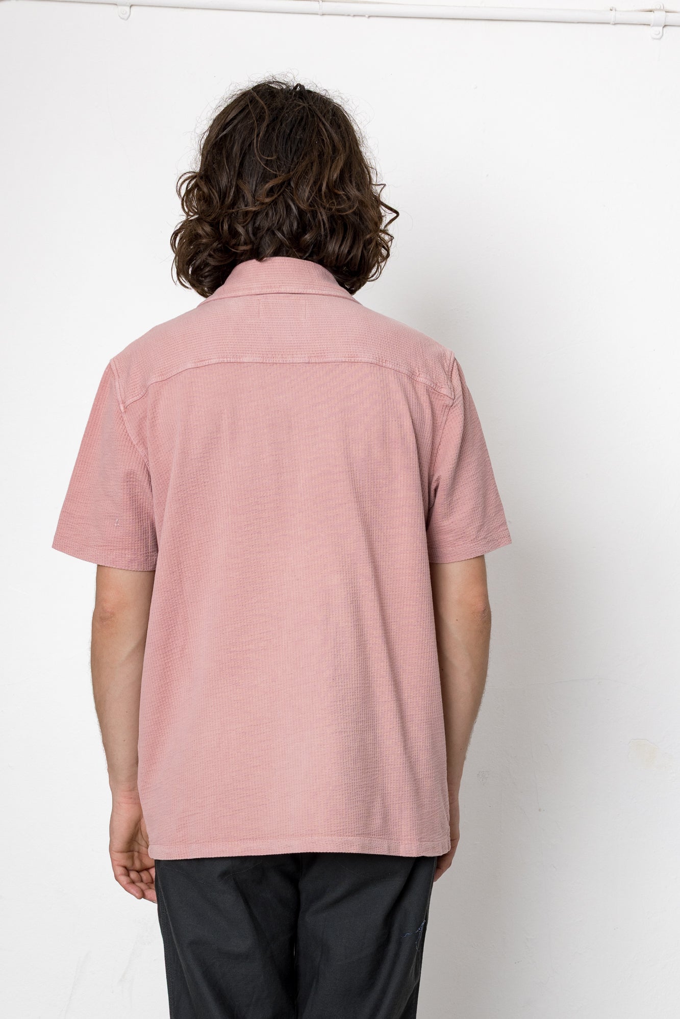 Person wearing a pink shirt against a white background