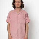 Man wearing a pink short-sleeve shirt against a white background