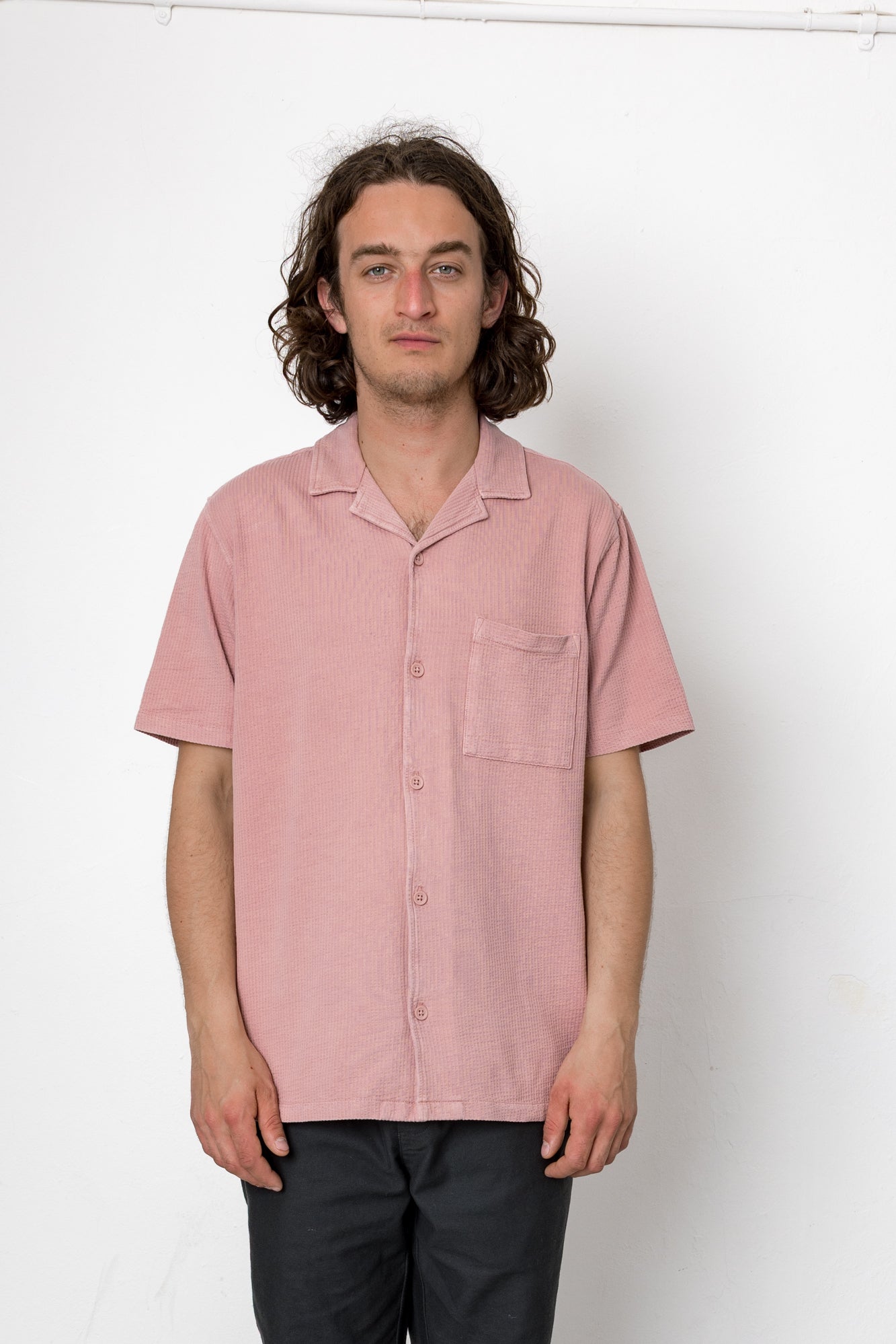 Man wearing a pink short-sleeve shirt against a white background