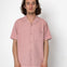 Man wearing a pink short-sleeve shirt against a white background