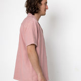 Person wearing a light pink shirt against a white background