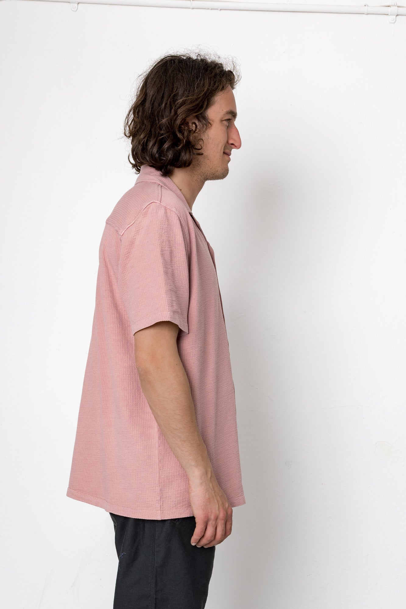 Person wearing a light pink shirt against a white background