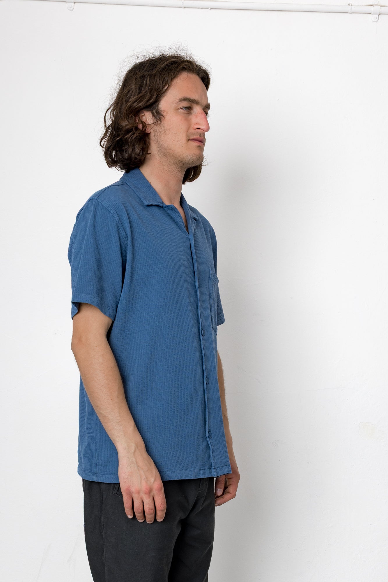 Man wearing a blue shirt standing against a white background