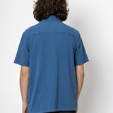Person wearing a blue shirt and black pants against a white background