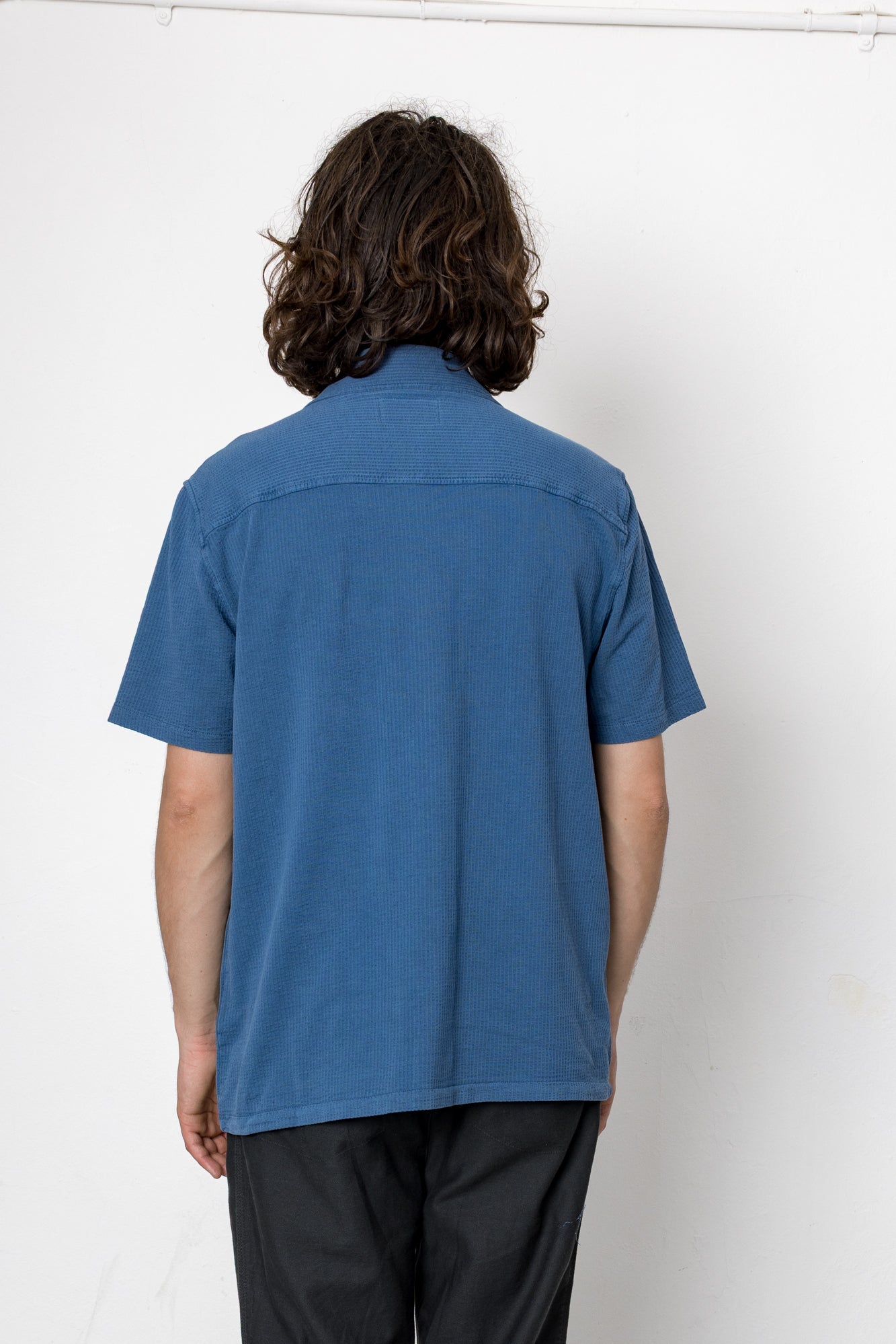 Person wearing a blue shirt and black pants against a white background
