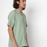Man wearing a light green shirt against a white background