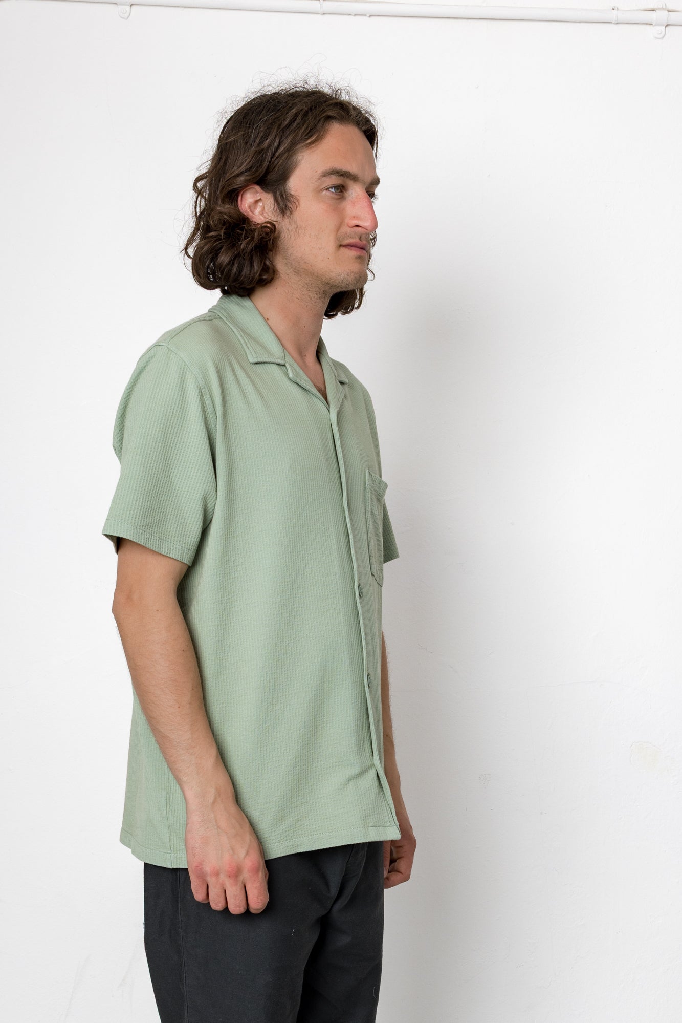 Man wearing a light green shirt against a white background