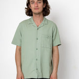 Man wearing a light green short-sleeve shirt against a white background