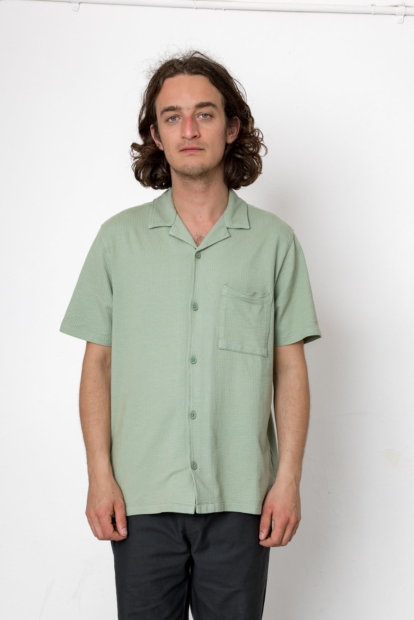Man wearing a light green short-sleeve shirt against a white background